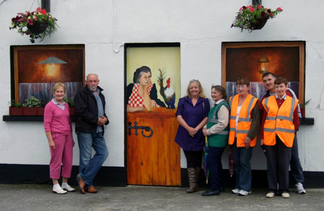 Therese Tierney and the mural, painted at the invitation of the Ballyleague Village Renewal and Tidy Towns